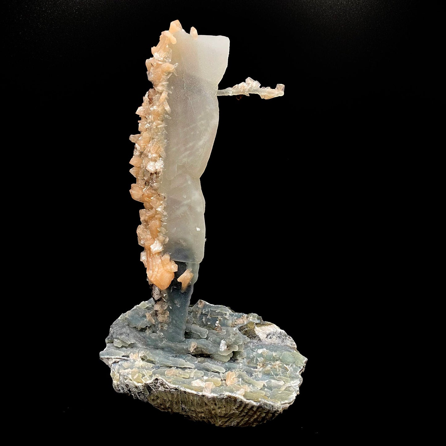 Towering calcite specimen coated in chalcedony and stilbite with a single distinctive, delicate stalactite growing sideways near the top termination, with stilbite blades of its own. The base is blue chalcedony stalactites with basalt on the bottom.