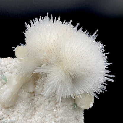 Glassy white mesolite needles in a spherical formation formed with stilbite and apophyllite on a mordenite matrix. Calcite adds smoky coloration to the end of each needle.