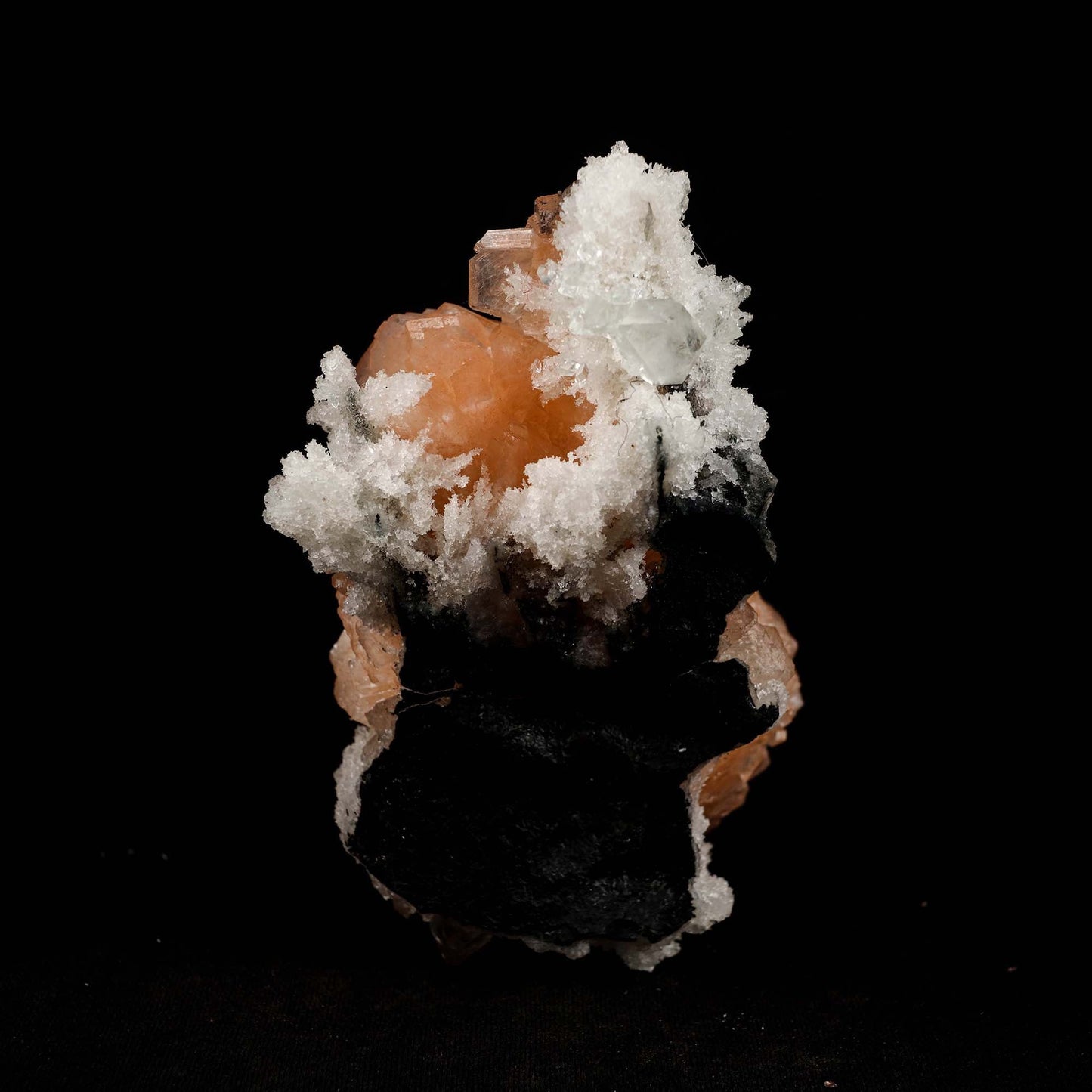 Pink Stilbite Cluster on Chalcedony Natural Mineral Specimen # B 5181 https://www.superbminerals.us/products/pink-stilbite-cluster-on-chalcedony-natural-mineral-specimen-b-5181 Features: Transparent green apophyllite crystals long with lustrous crystal faces and steep pyramidal terminations on matrix coated with lustrous peach-baggie coloured Stilbite crystals of varying sizes. Primary Mineral(s): Stilbite Secondary Mineral(s): N/AMatrix: Chalcedony 5 Inch x 3 InchWeight : 298