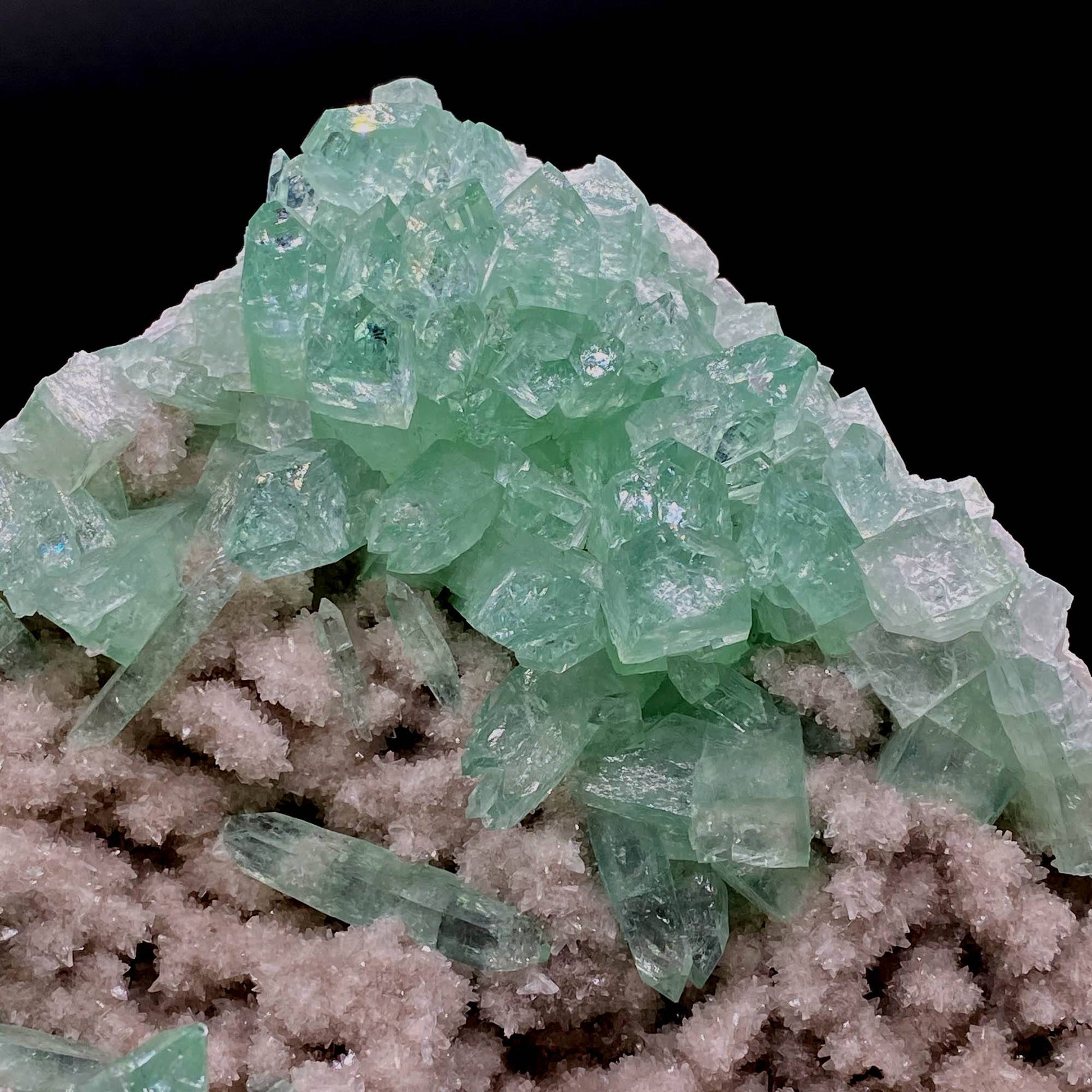 Green Apophyllite Sparkling Crystals on Heulandite Cluster # Q2  https://www.superbminerals.us/products/green-apophyllite-sparkling-crystals-on-heulandite-cluster-q2  Features:Sparkling cluster of green Apophyllite crystals in a radiating formation on matrix lined with creme-colored stilbite crystals in aggregates. The apophyllite crystals are fully terminated with vivd green color and glassy luster.&nbsp;Primary Mineral(s): ApophylliteSecondary Mineral(s): N/A Matrix: Heulandite