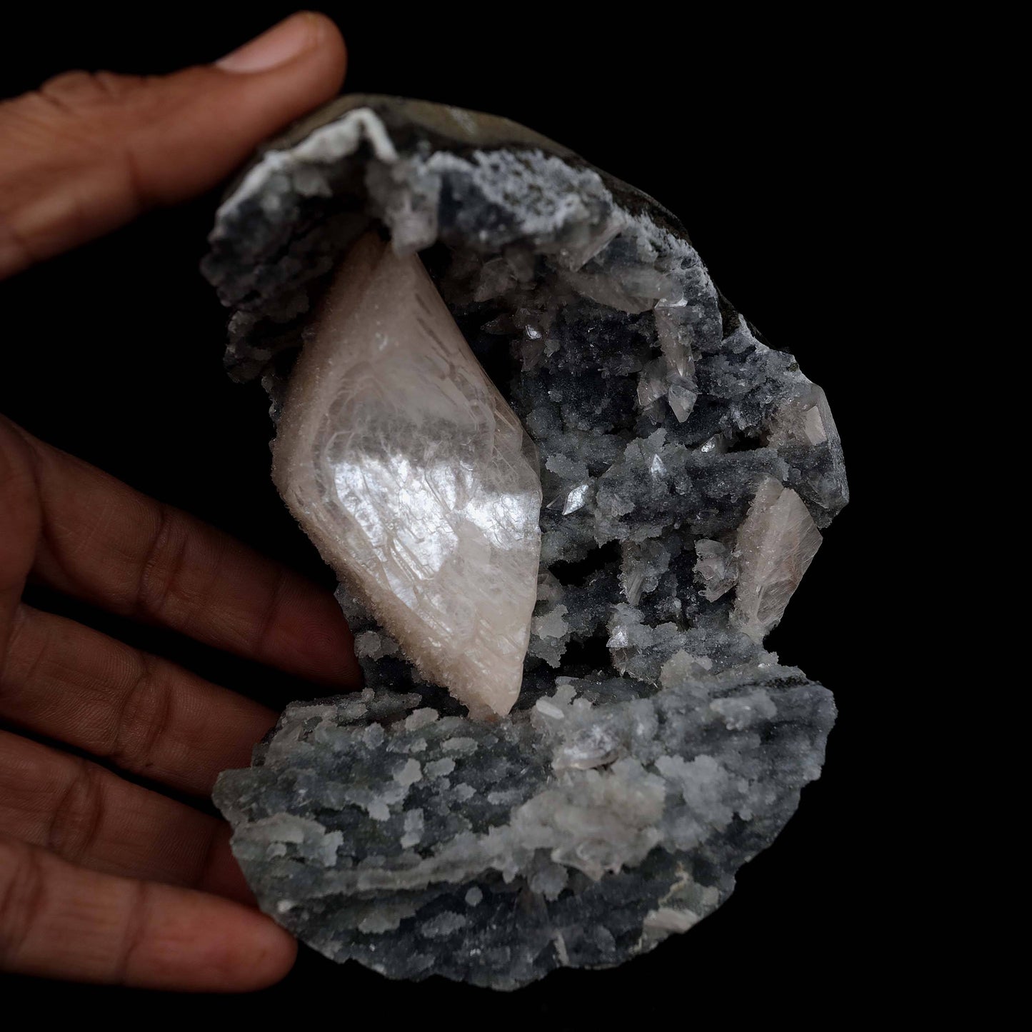 Heulandite Crystal Inside Black Chalcedony Geode Natural Mineral Speci…  https://www.superbminerals.us/products/heulandite-crystal-inside-black-chalcedony-geode-natural-mineral-specimen-b-4491  Features:A stunning wedge heulandite crystal is forcefully placed in a sculptural, well-prepared basalt vug bordered with a sharply contrasting sparkling grey drusy chalcedony.The magnificent glassy, iridescent, transparent parallel-growth bladed heulandite has a lovely rich coral-pink hue with unique curving 